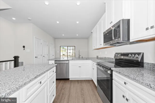 a kitchen with granite countertop a refrigerator stove top oven and sink