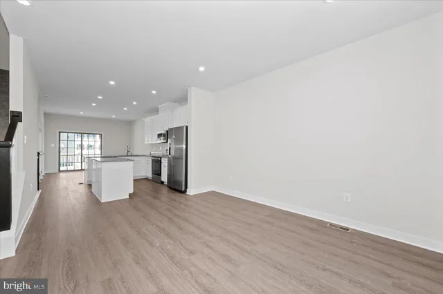 a kitchen with a center island wooden floor and stainless steel appliances