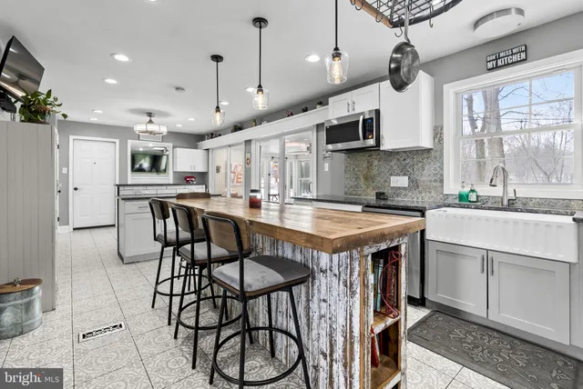 a kitchen with kitchen island a dining table chairs and white cabinets