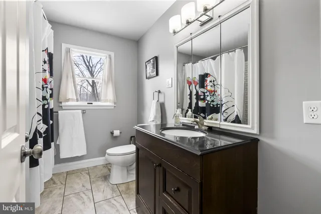 a bathroom with a granite countertop sink a toilet and a mirror