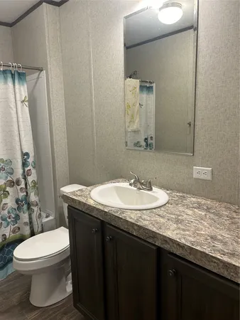 a bathroom with a granite countertop sink toilet and mirror