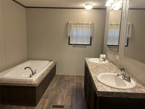 a bathroom with a granite countertop sink a mirror and a bathtub