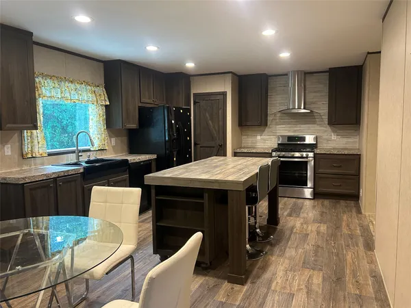 a kitchen with stainless steel appliances granite countertop a sink stove refrigerator and chairs