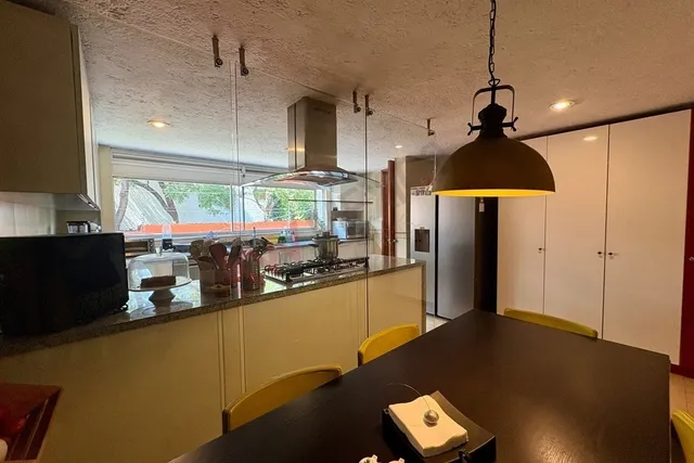 a kitchen with stainless steel appliances granite countertop a refrigerator a sink dishwasher a stove and a dining table with wooden floor