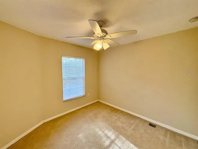an empty room with a window and a ceiling fan