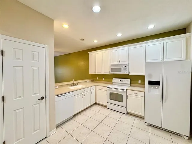 a kitchen with white cabinets and white appliances