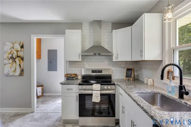 a kitchen with granite countertop a stove a sink a refrigerator and a window