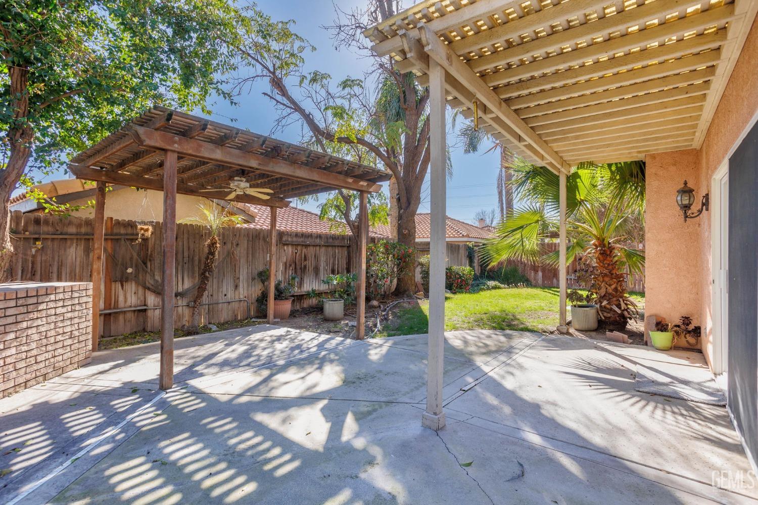 Undisclosed Address Bakersfield, CA 93311 - Photo 47 of 52 a view of a patio with table and chairs under an umbrella with a small yard