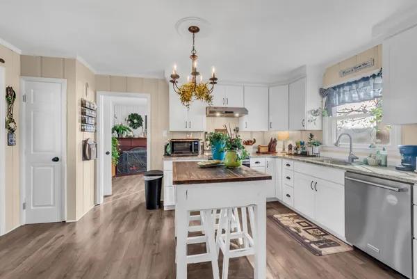 a kitchen with stainless steel appliances granite countertop a refrigerator a stove a sink dishwasher and white cabinets with wooden floor