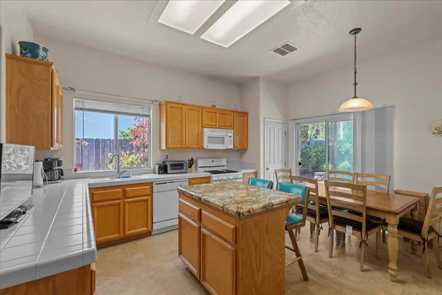 a kitchen with a stove a sink a kitchen island with a dining table and chairs