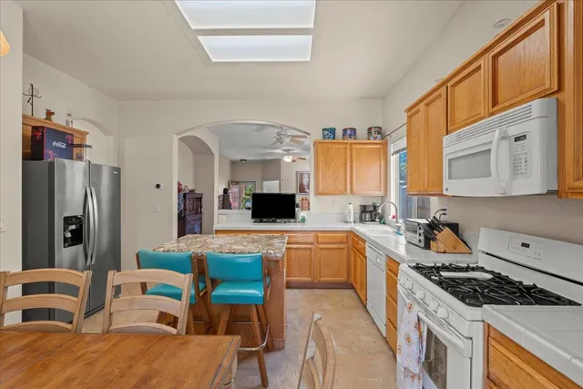 a kitchen with stainless steel appliances granite countertop a stove a sink dishwasher a refrigerator a dining table and chairs with wooden floor