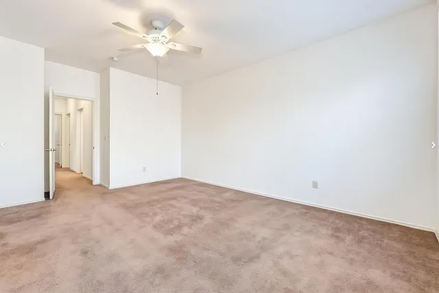 an empty room with a ceiling fan and a window