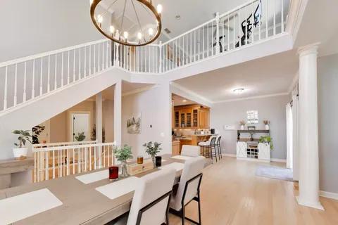 a dining room with furniture a rug a chandelier and a wooden floor