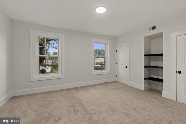 an empty room with closet and windows