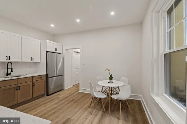 a kitchen with a dining table chairs and refrigerator