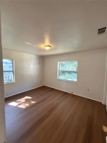 an empty room with wooden floor and windows