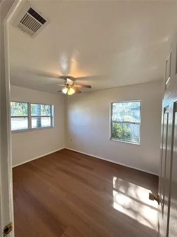 an empty room with windows and ceiling fan