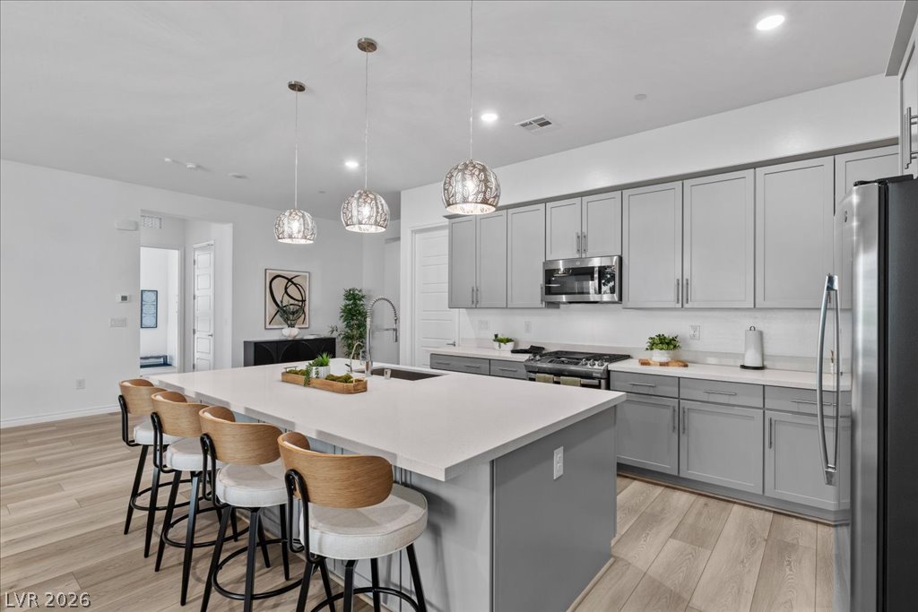 20 Charlotte Ridge Place Henderson, NV 89011 - Photo 11 of 33 The kitchen features stylish light gray cabinetry, an oversized island with seating, and modern pendant lighting.