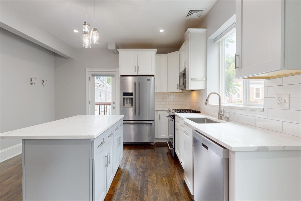 61 Charlotte Street, Unit 2 Boston, MA 02121 - Photo 5 of 36 a kitchen with a sink a stove a refrigerator and white cabinets