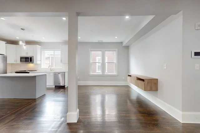 a kitchen with stainless steel appliances granite countertop a refrigerator a sink dishwasher a stove and white countertops with wooden floor