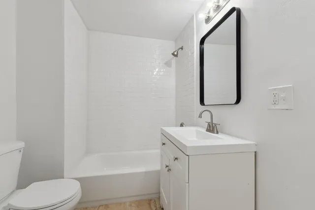 a bathroom with a toilet sink vanity tub and mirror