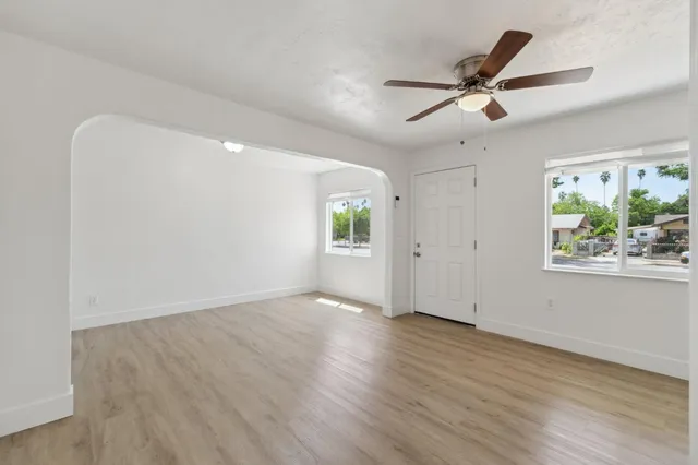 a view of an empty room with window and wooden floor