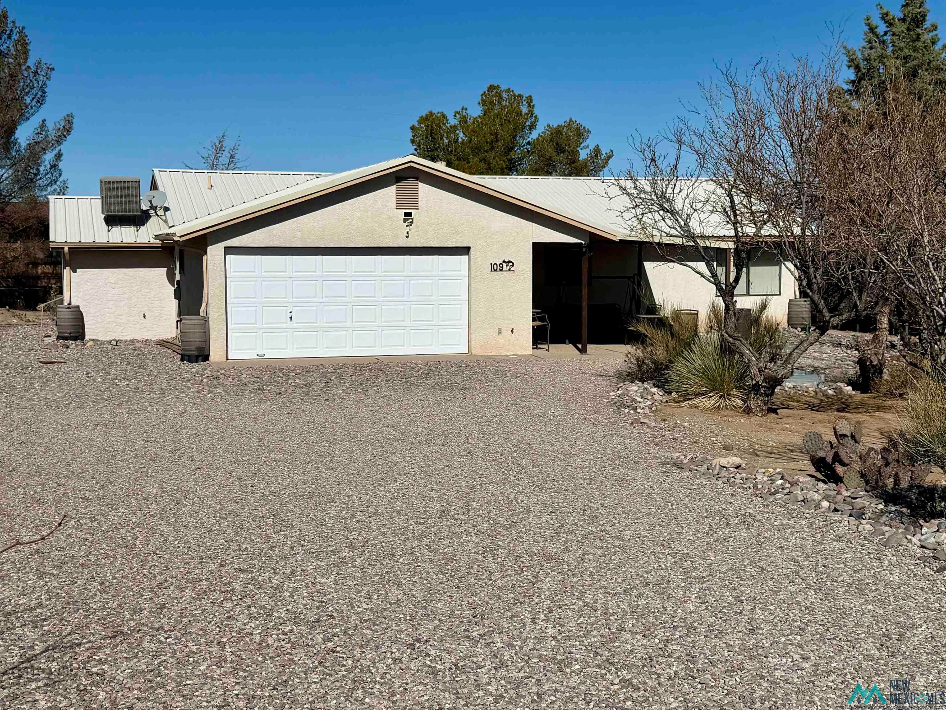 109 Mimbres Road Elephant Butte, NM 87935 - Photo 2 of 27 View of front facade with stucco siding, a metal roof, and driveway