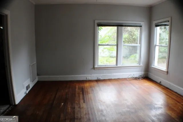 an empty room with wooden floor and windows