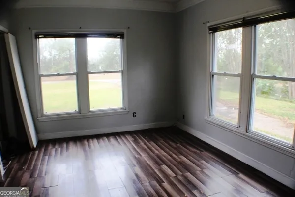 a view of an empty room with wooden floor and a window