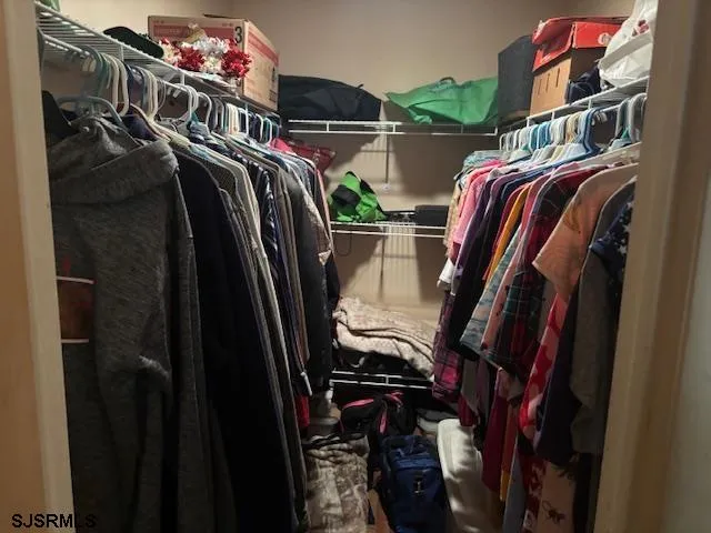 a view of walk in closet with clothes and shoes