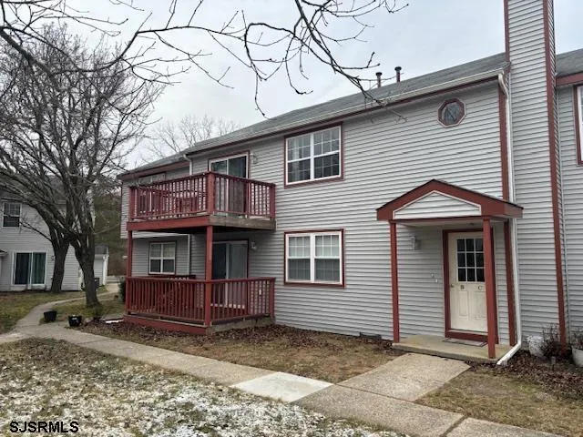 a view of a house with a small yard and large tree