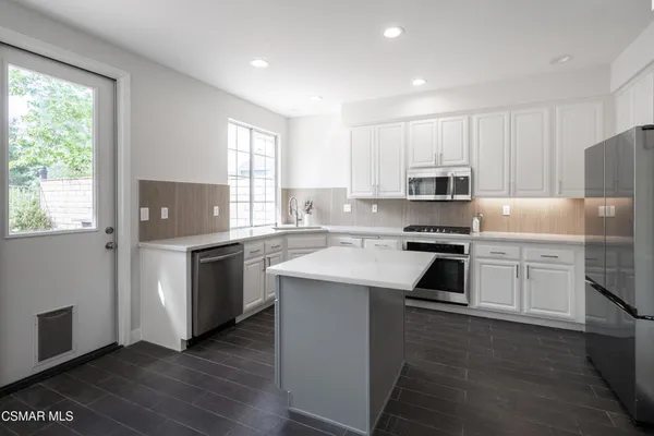 a kitchen with a refrigerator and a stove top oven