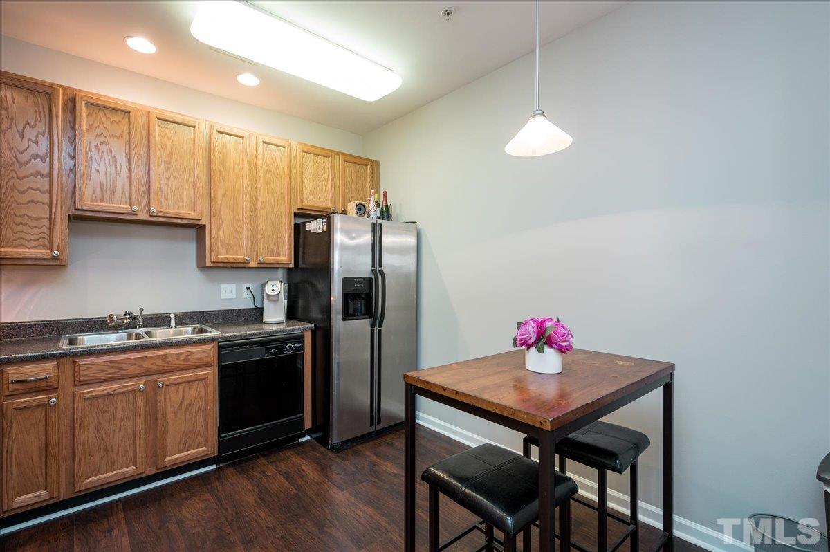 2210 Raven Road, Unit 108 Raleigh, NC 27614 - Photo 10 of 22 a kitchen with stainless steel appliances granite countertop a refrigerator a sink dishwasher a stove a dining table and chairs with wooden floor