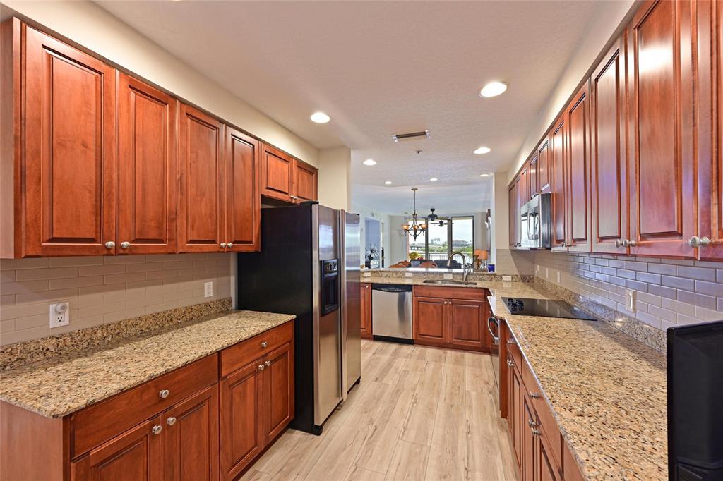 615 Riviera Dunes Way, Unit 107 Palmetto, FL 34221 - Photo 19 of 50 a kitchen with stainless steel appliances granite countertop a refrigerator a sink dishwasher a stove and large countertops with wooden floor