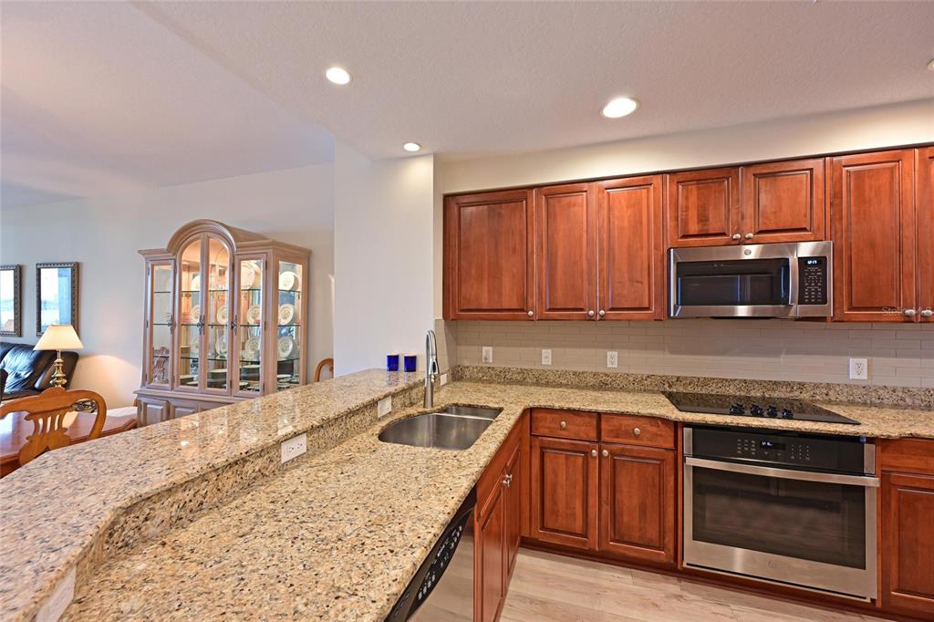 615 Riviera Dunes Way, Unit 107 Palmetto, FL 34221 - Photo 20 of 50 a kitchen with stainless steel appliances granite countertop a stove a sink and a microwave