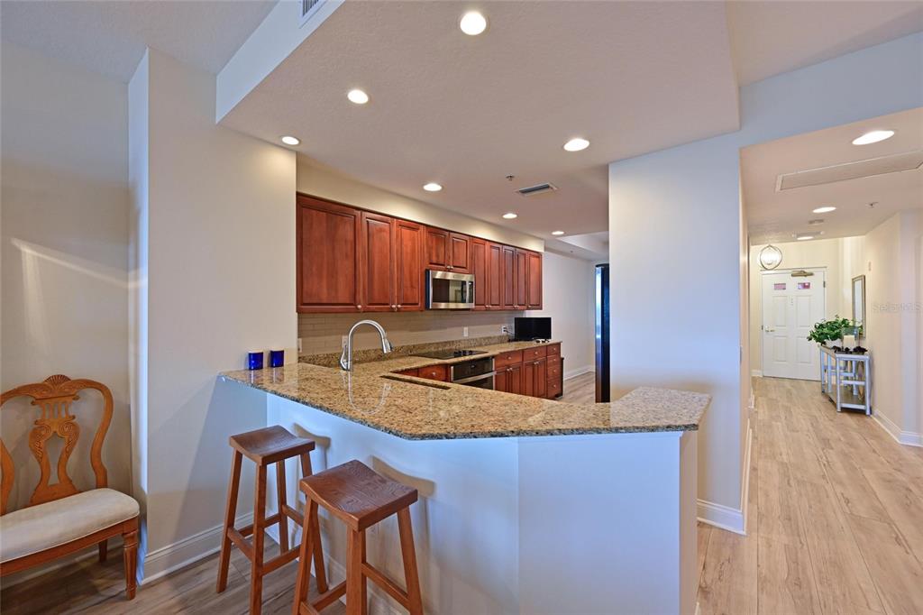 615 Riviera Dunes Way, Unit 107 Palmetto, FL 34221 - Photo 21 of 50 a kitchen with stainless steel appliances granite countertop a table chairs sink refrigerator and microwave