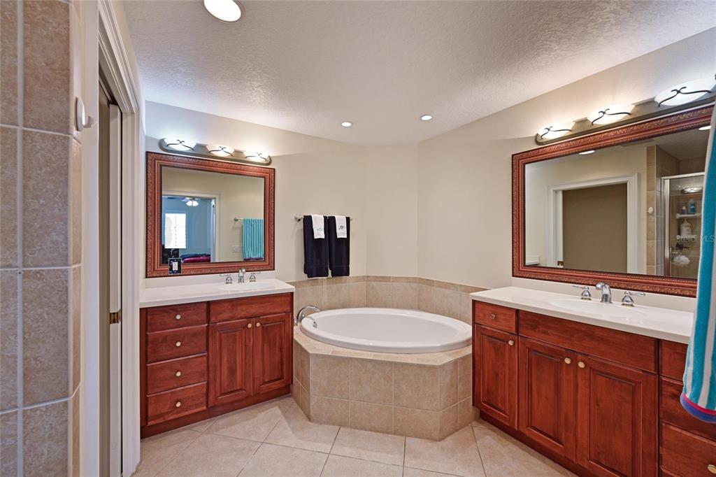 615 Riviera Dunes Way, Unit 107 Palmetto, FL 34221 - Photo 30 of 50 a bathroom with a tub a sink double vanity and a mirror
