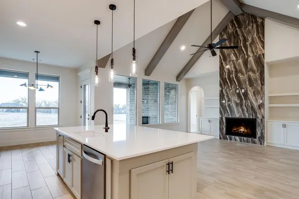 a kitchen with a sink a faucet a fireplace and a floor to ceiling window
