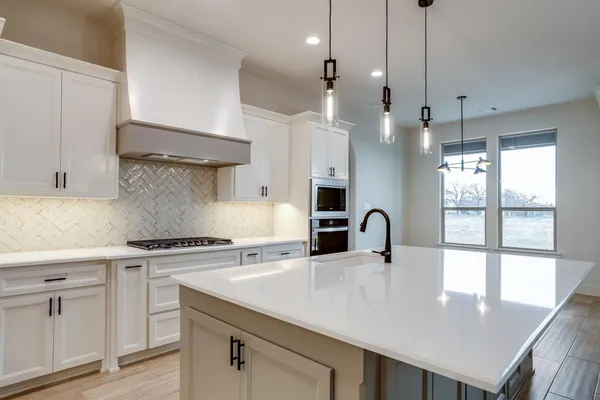 a kitchen with granite countertop a sink a counter space appliances and cabinets