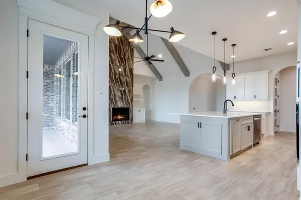 a large kitchen with granite countertop a stove a sink dishwasher and a refrigerator with wooden floor