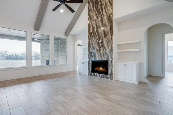a view of an empty room with wooden floor fireplace and a window