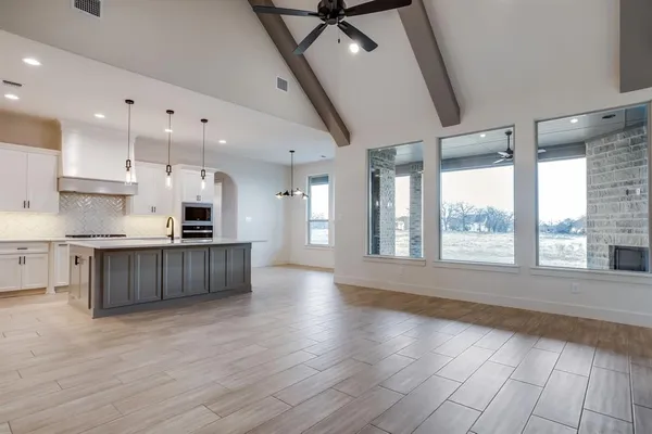 a large kitchen with stainless steel appliances granite countertop a large counter top a stove and a wooden floors