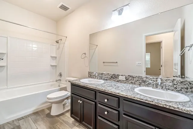 a bathroom with a granite countertop sink toilet mirror and bathtub
