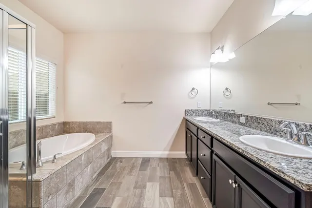 a bathroom with a granite countertop sink a bathtub a mirror and shower