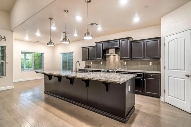 a large kitchen with granite countertop a large counter top a sink stainless steel appliances and cabinets
