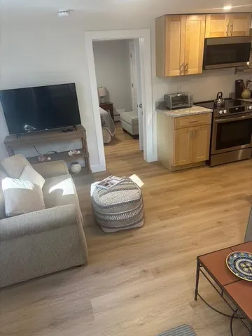 a kitchen with stainless steel appliances a stove a sink cabinets and a wooden floor