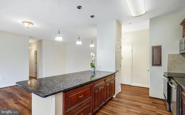 a kitchen with stainless steel appliances granite countertop a refrigerator a stove and a sink with wooden floors