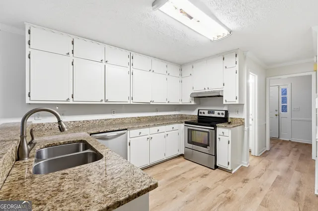 a kitchen with granite countertop a sink stainless steel appliances and cabinets