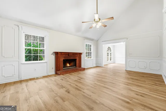 an empty room with wooden floor fireplace and windows