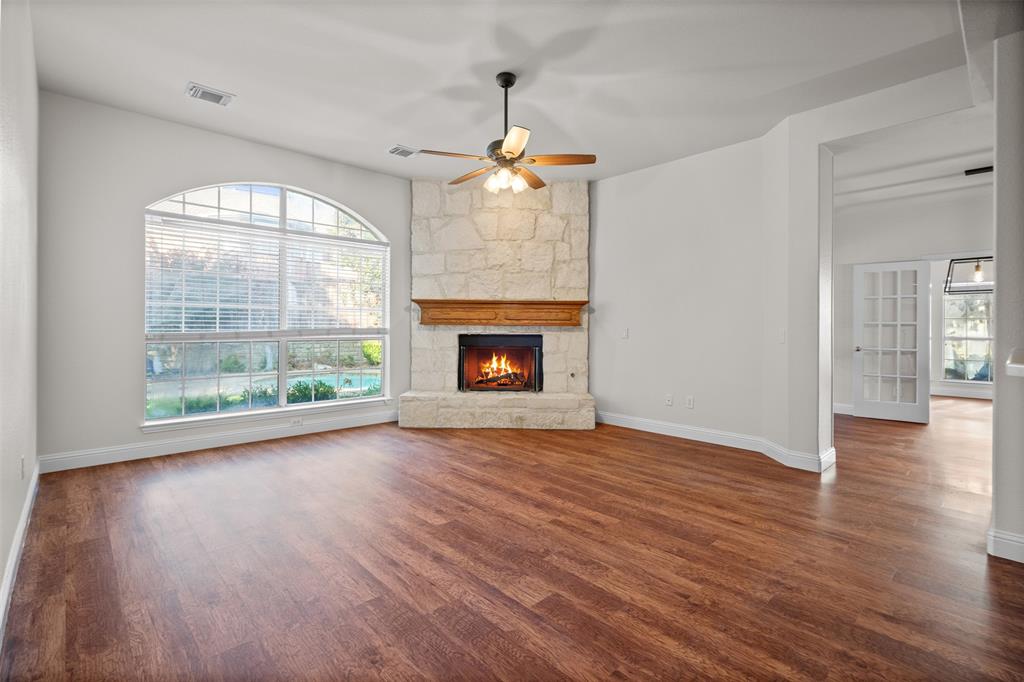 4405 Ridgecove Drive Rowlett, TX 75088 - Photo 6 of 37 Vaulted ceiling, arched window with blinds, wood-finish flooring, stone-surround fireplace with wood mantel, and a ceiling fan